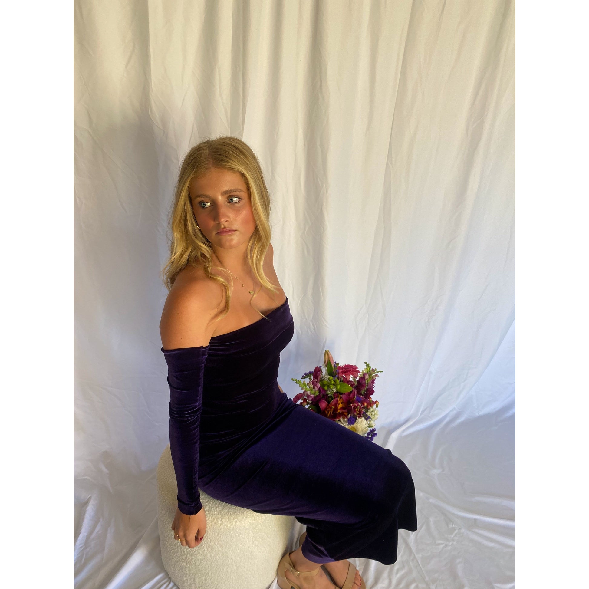 7th and York Strapless Midi Dress in Blackberry, Velvet Material - comes with optional sleeves. Perfect for a variety of formal events. Size 6 dress and Size S sleeves. Sitting down side view with sleeves