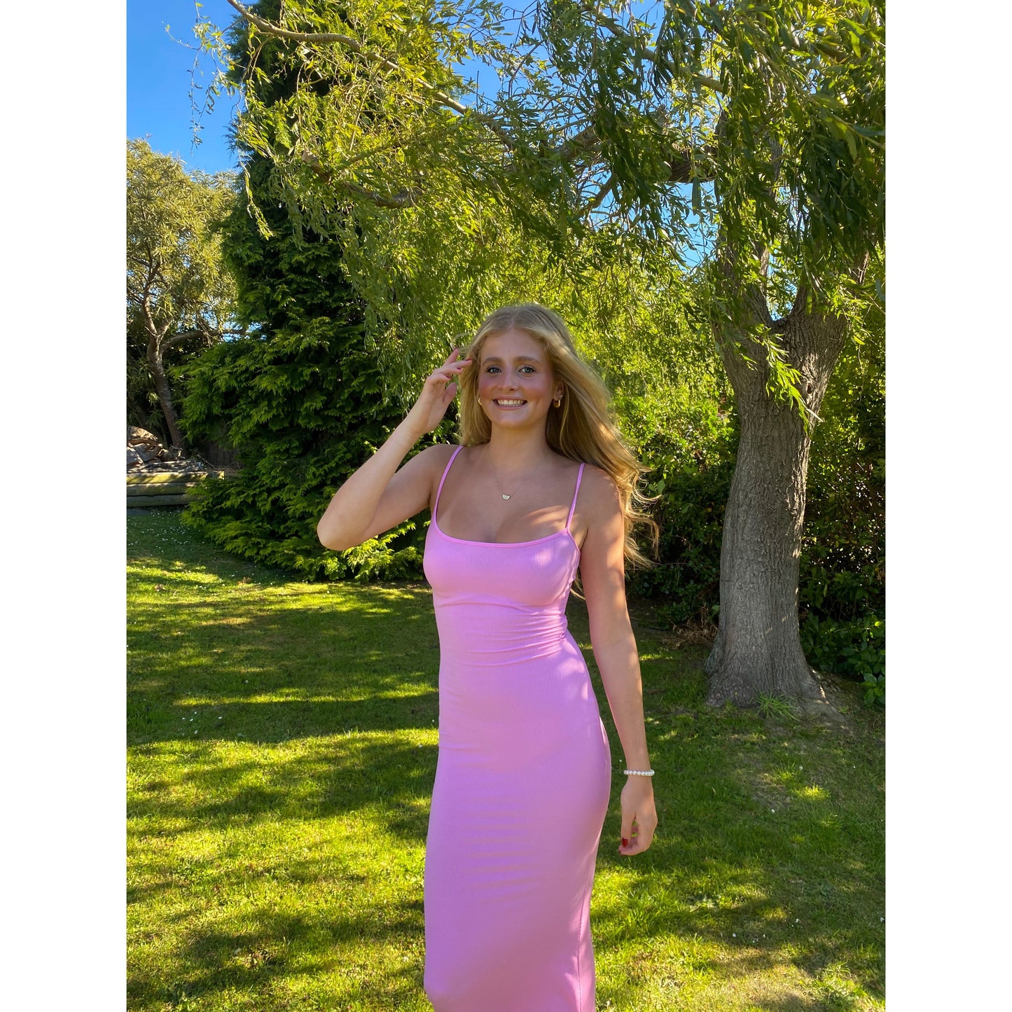 SKIMS Long Slip Dress in Cotton Candy Pink, Size M. Featuring a body hugging fit, straight neck and adjustable spaghetti straps. Can be dressed up or down. Dress can appear semi sheer depending on how much it is stretched when on. Can be dressed up or down. Front on view of dress.