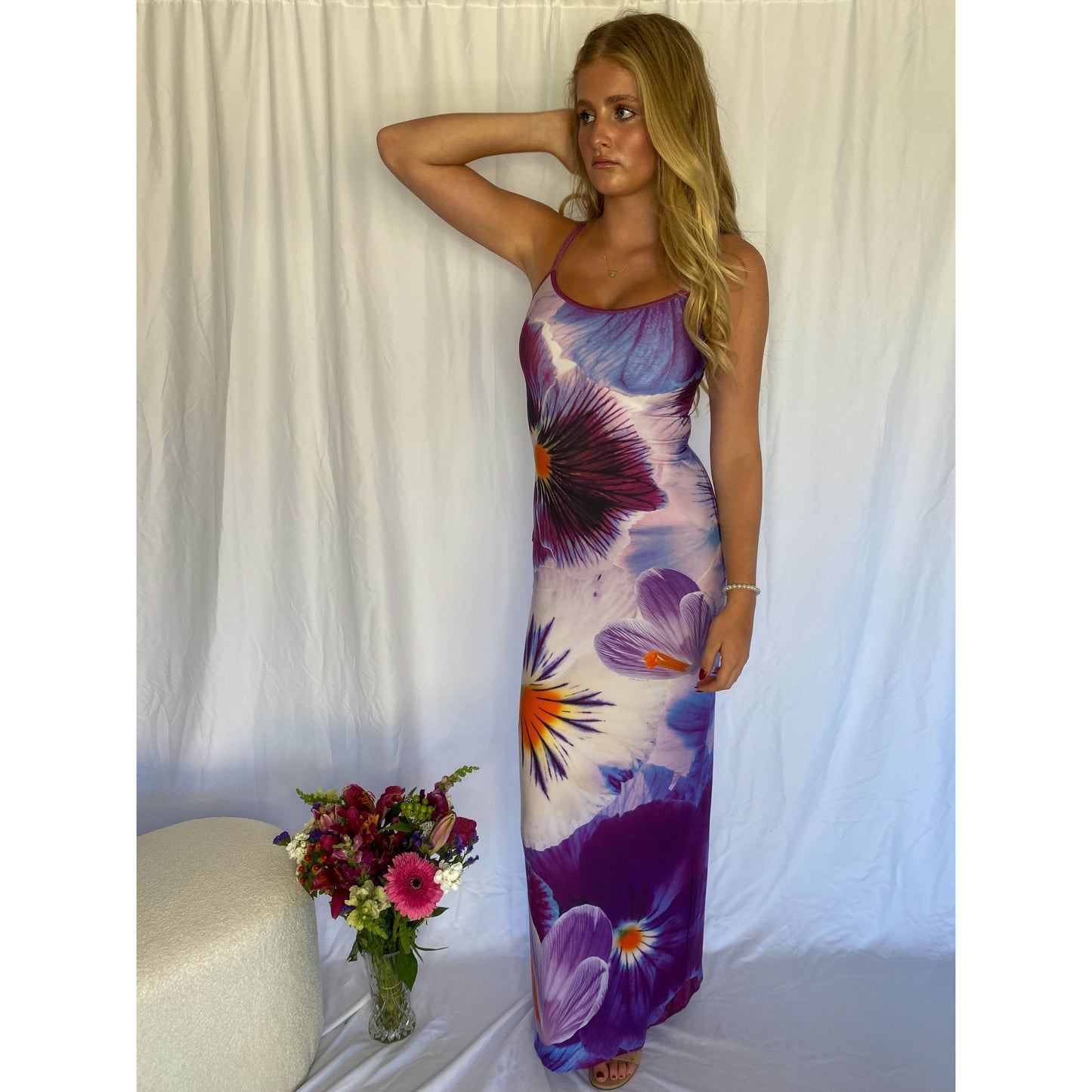 With Harper Lu Indigo Slip, Size S. Featuring an accentuated waistline, adjustable straps, a rear split, and fully lined, this dress is designed to skim the body. With an amethyst print with a few pops of tangelo. Perfect for formals, birthdays, etc. Front on standing view of dress.