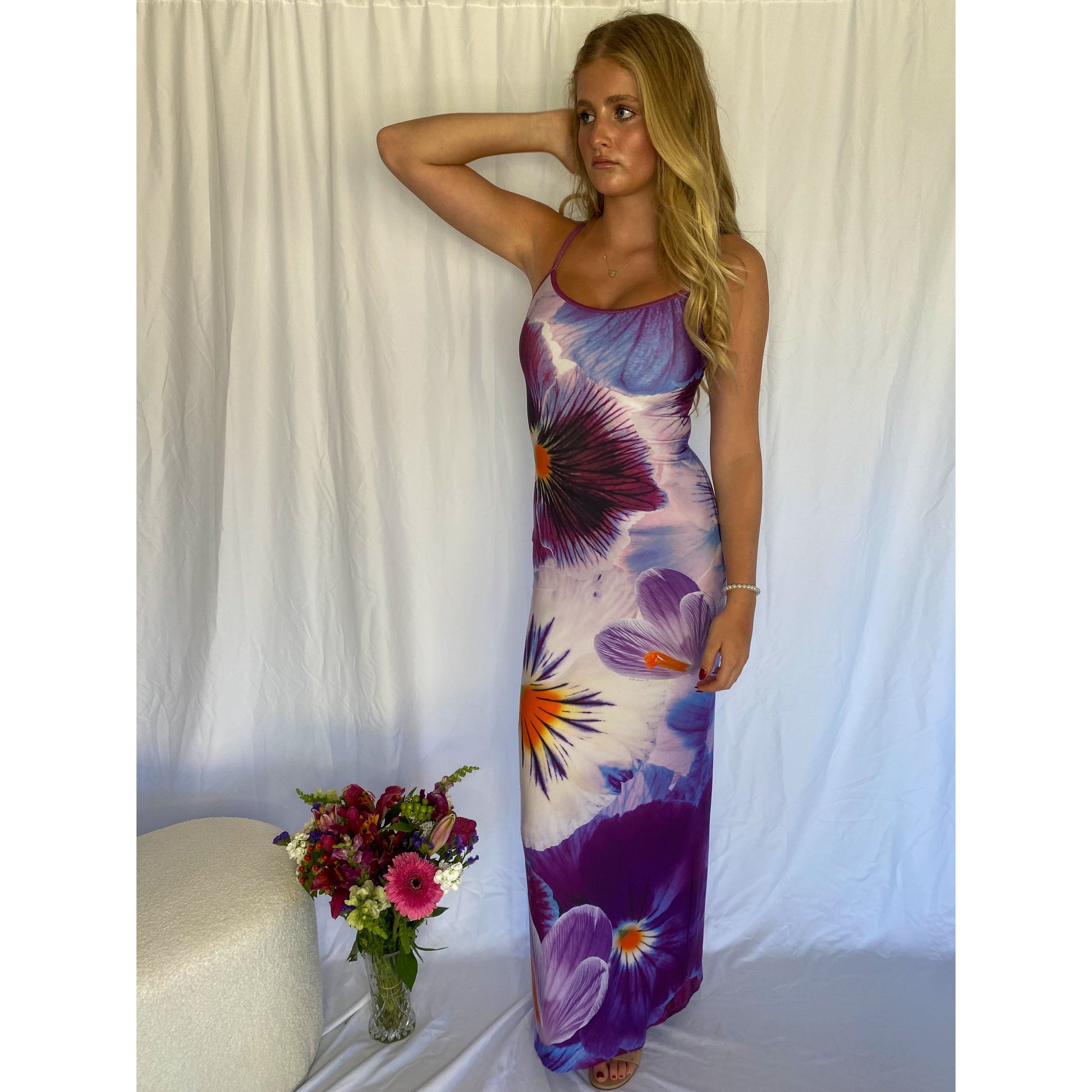 With Harper Lu Indigo Slip, Size S. Featuring an accentuated waistline, adjustable straps, a rear split, and fully lined, this dress is designed to skim the body. With an amethyst print with a few pops of tangelo. Perfect for formals, birthdays, etc. Front on standing view of dress.