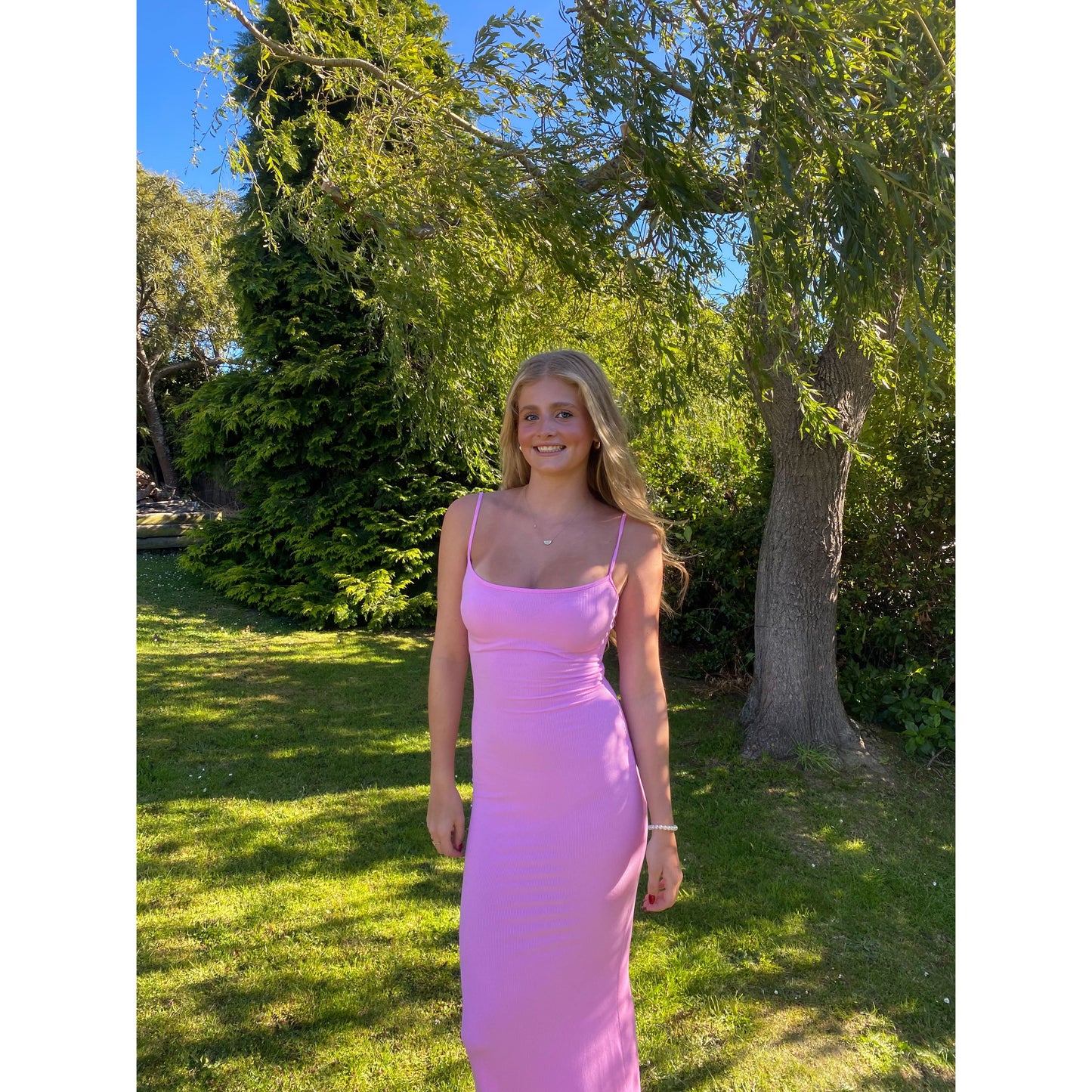 SKIMS Long Slip Dress in Cotton Candy Pink, Size M. Featuring a body hugging fit, straight neck and adjustable spaghetti straps. Can be dressed up or down. Dress can appear semi sheer depending on how much it is stretched when on. Can be dressed up or down. Front on view of dress.