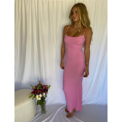 SKIMS Long Slip Dress in Cotton Candy Pink, Size M. Featuring a body hugging fit, straight neck and adjustable spaghetti straps. Can be dressed up or down. Dress can appear semi sheer depending on how much it is stretched when on. Can be dressed up or down. Front on full length view of dress.