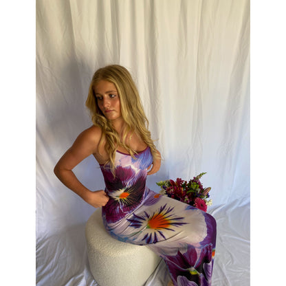 With Harper Lu Indigo Slip, Size S. Featuring an accentuated waistline, adjustable straps, a rear split, and fully lined, this dress is designed to skim the body. With an amethyst print with a few pops of tangelo. Perfect for formals, birthdays, etc. Front on sitting down view of dress.