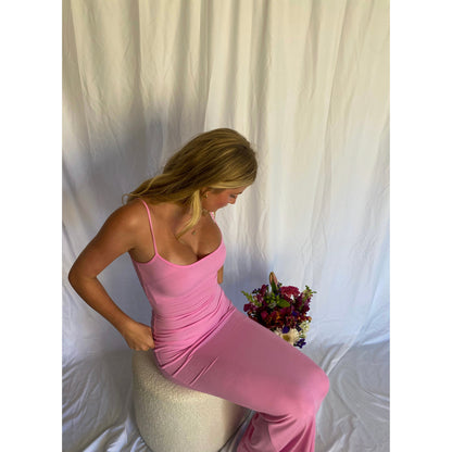 SKIMS Long Slip Dress in Cotton Candy Pink, Size M. Featuring a body hugging fit, straight neck and adjustable spaghetti straps. Can be dressed up or down. Dress can appear semi sheer depending on how much it is stretched when on. Can be dressed up or down. Front on sitting down view of dress.