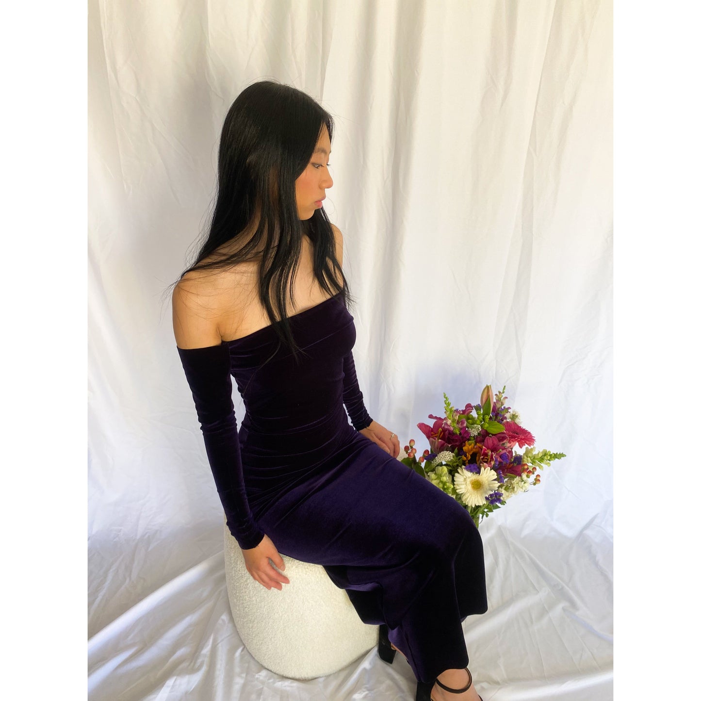 7th and York Strapless Midi Dress in Blackberry, Velvet Material - comes with optional sleeves. Perfect for a variety of formal events. Size 6 dress and Size S sleeves. Above slightly to the side view of sitting down in dress