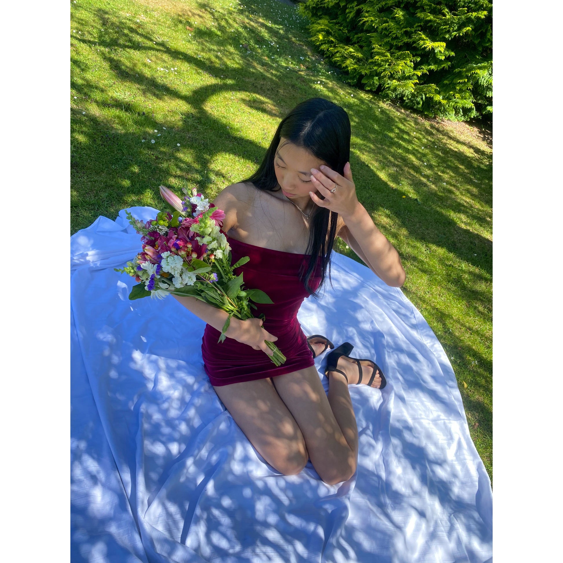 7th and York Strapless Mini Dress in Magenta, Velvet Material. Perfect for events like the races, birthdays etc. Size 6/XS dress. Sitting down above view off dress outside, flowers partially covering some of dress