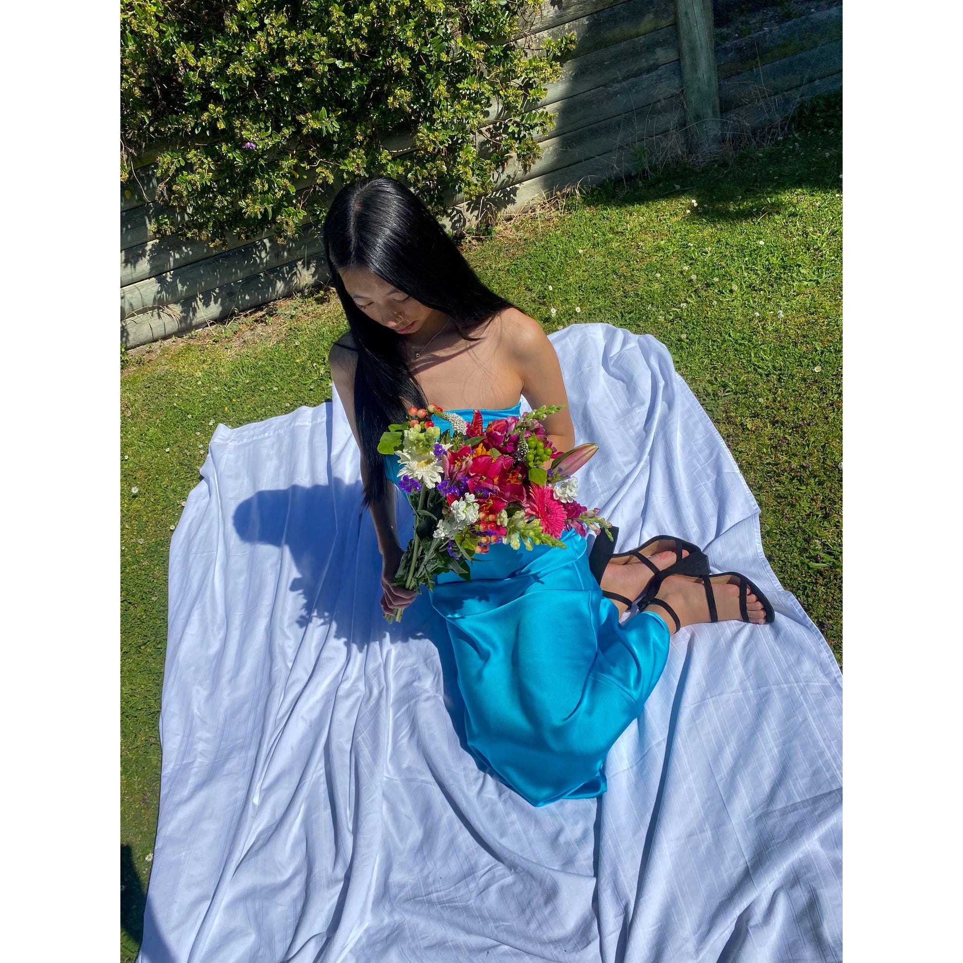 Miya Maxi in Turquoise Blue, Size 8/S. Strapless design with a tight yet flowy satiny material with a zip up side. Perfect for races, graduation, formals etc. Sitting down view of dress.