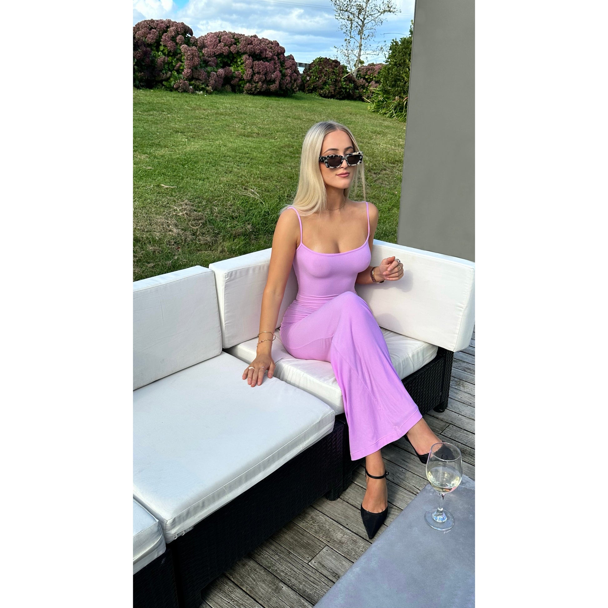 SKIMS Long Slip Dress in Petal Pink, Size XS and M. Featuring a body hugging fit, straight neck and adjustable spaghetti straps. Can be dressed up or down. Dress can appear semi sheer depending on how much it is stretched when on. Can be dressed up or down. Front on sitting down view of dress.