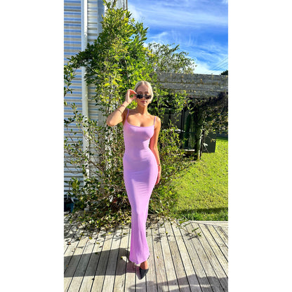 SKIMS Long Slip Dress in Petal Pink, Size XS and M. Featuring a body hugging fit, straight neck and adjustable spaghetti straps. Can be dressed up or down. Dress can appear semi sheer depending on how much it is stretched when on. Can be dressed up or down. Front on full length view of dress.