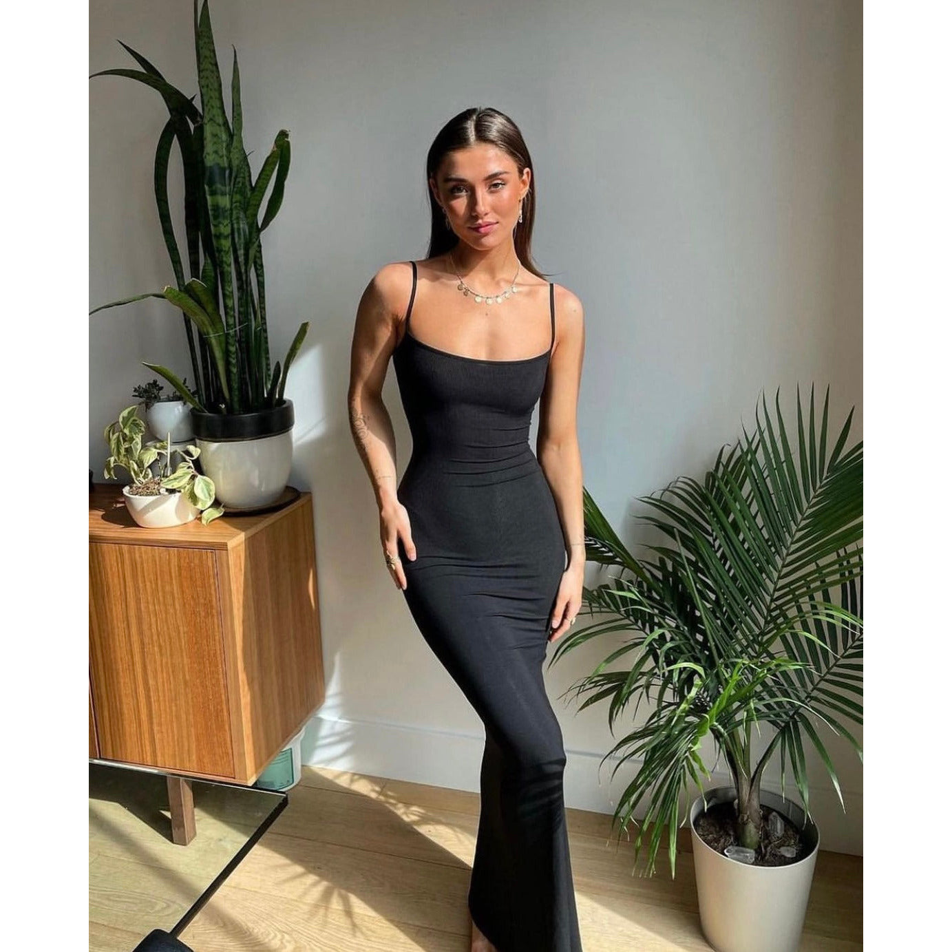 SKIMS Long Slip Dress in Onyx, Size XS and M. Featuring a body hugging fit, straight neck and adjustable spaghetti straps. Can be dressed up or down. Front on full length view of dress.