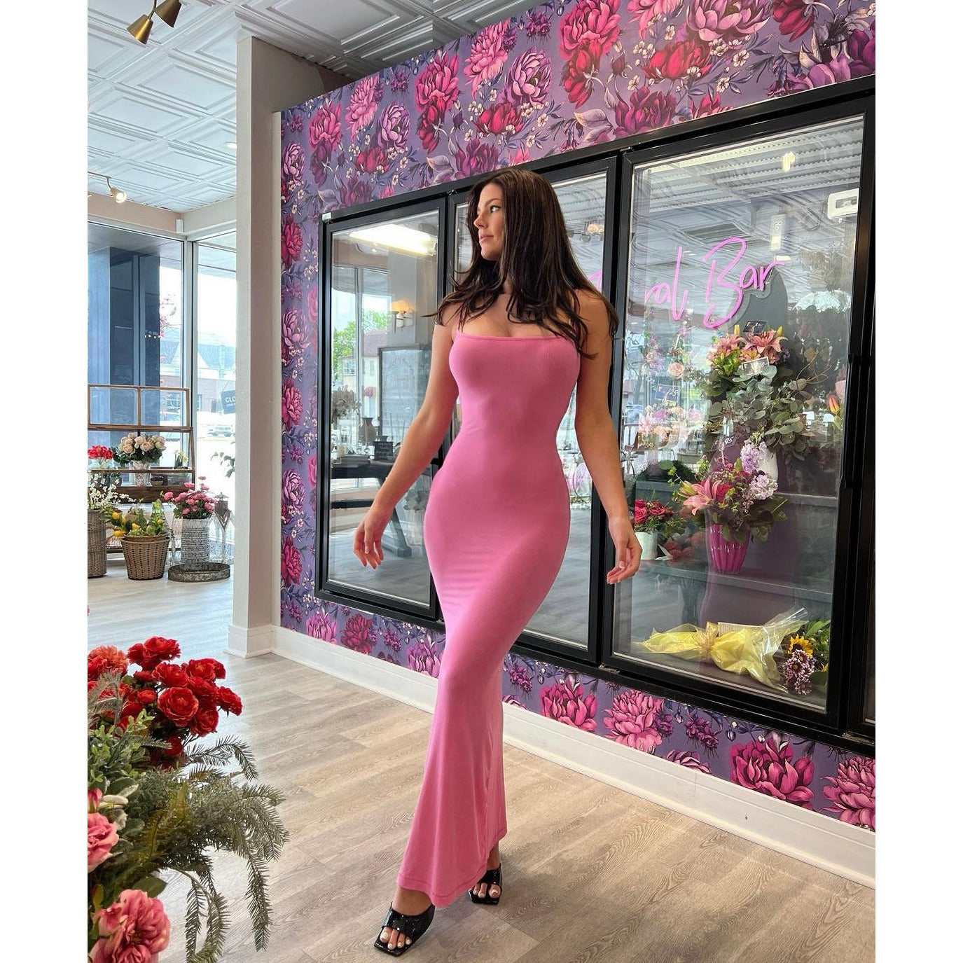 SKIMS Long Slip Dress in Bubblegum Pink, Size M. Featuring a body hugging fit, straight neck and adjustable spaghetti straps. Can be dressed up or down. Dress can appear semi sheer depending on how much it is stretched when on. Can be dressed up or down. Front on full length view of dress.