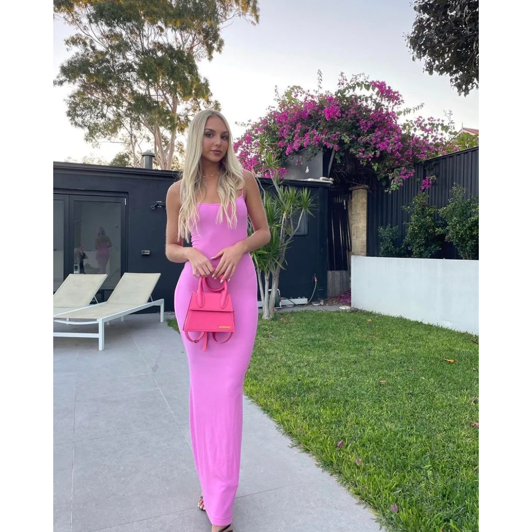 SKIMS Long Slip Dress in Bubblegum Pink, Size M. Featuring a body hugging fit, straight neck and adjustable spaghetti straps. Can be dressed up or down. Dress can appear semi sheer depending on how much it is stretched when on. Can be dressed up or down. Front on full length view.